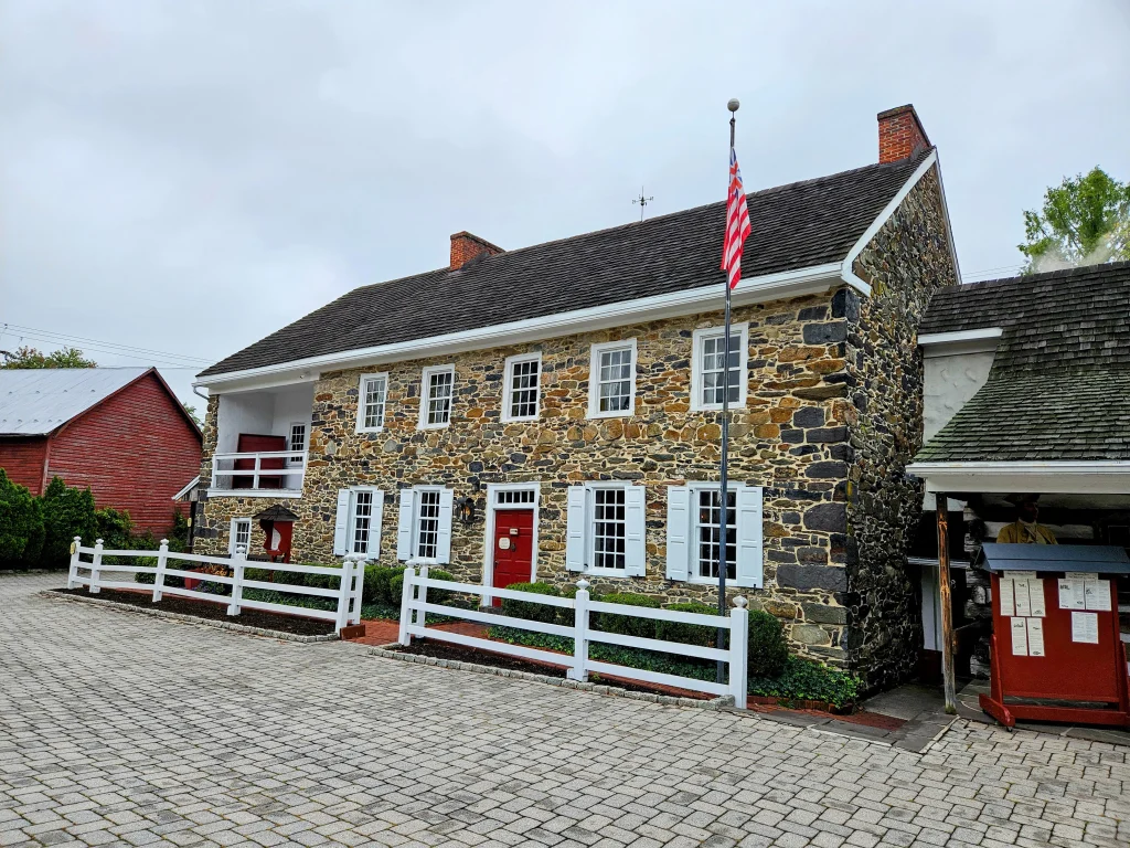 The stone facade, red entrance and white fence of Dobbin House, photographed in September 2024.