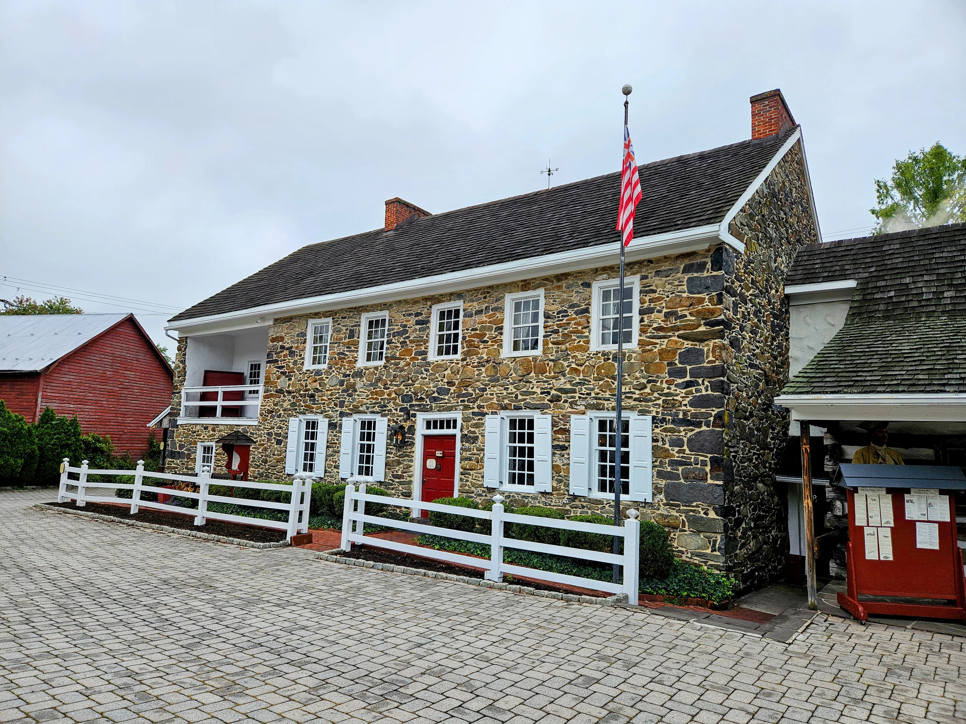 The stone facade, red entrance and white fence of Dobbin House, photographed in September 2024.