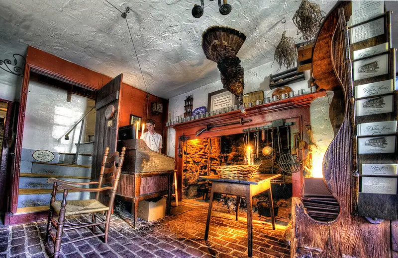 A glowing hearth with cooking utensils and historic furnishings inside Dobbin House.