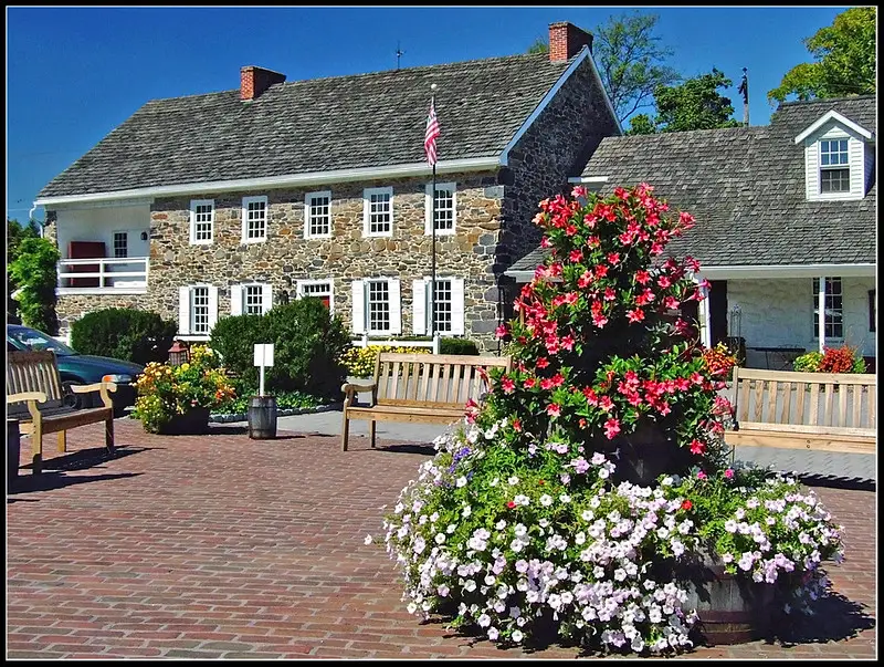 Colorful flowers and benches in front of the historic Dobbin House exterior.