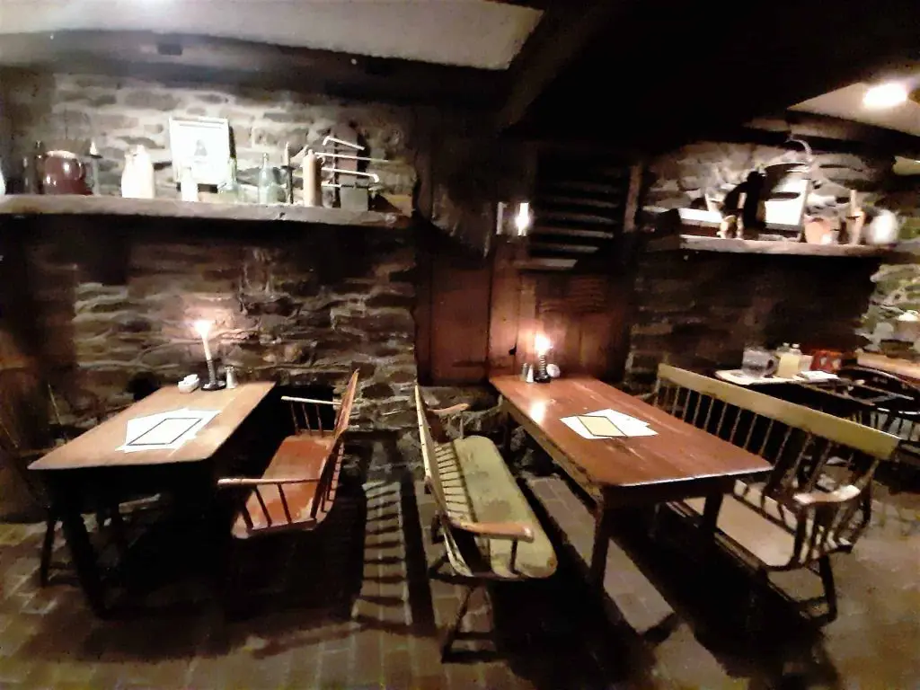Candlelit tables beneath exposed beams beside stone walls in the Springhouse Tavern.